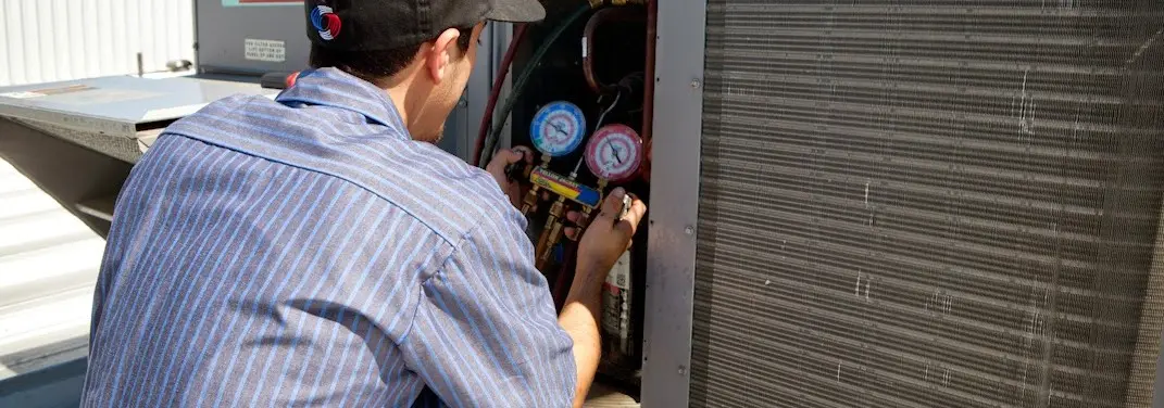 HVAC technician servicing a condenser unit in Robinson